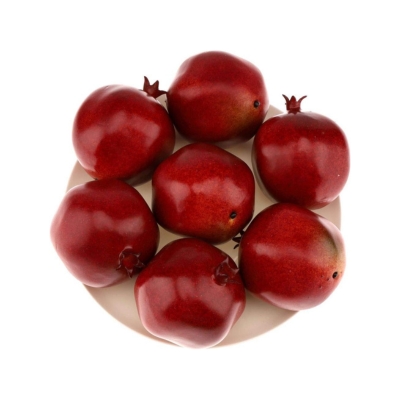 Five pomegranates on a plate, serving as a festive Christmas candle centerpiece, placed on a white background.