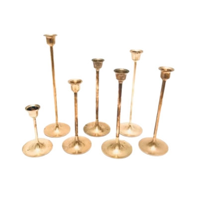 A group of brass candlesticks on a white background, creating an elegant Christmas candle centerpiece.