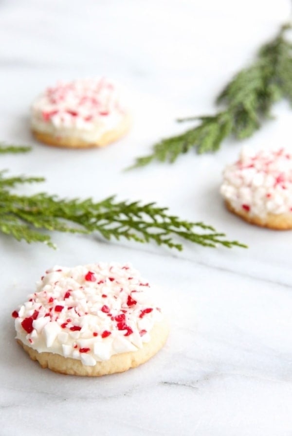 frosted peppermint cookies on marble countertop with holly leaves