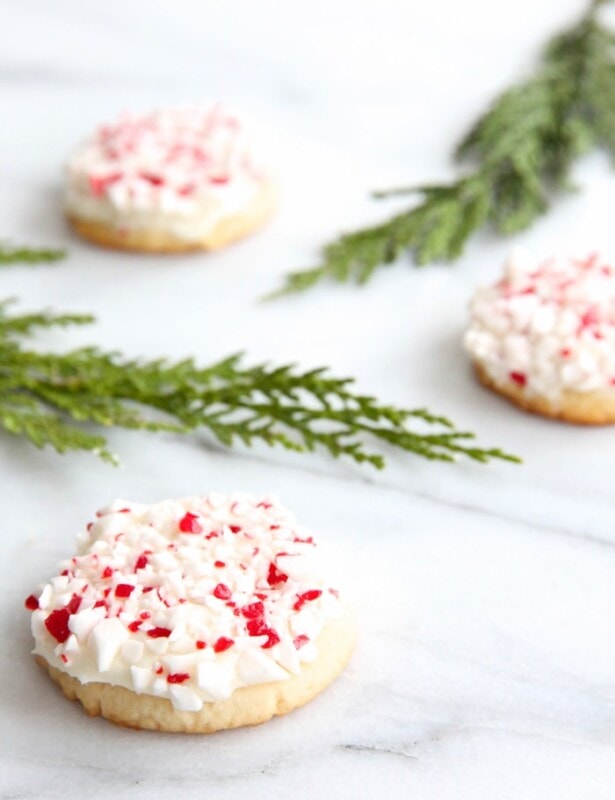 frosted peppermint cookies on marble countertop with holly leaves