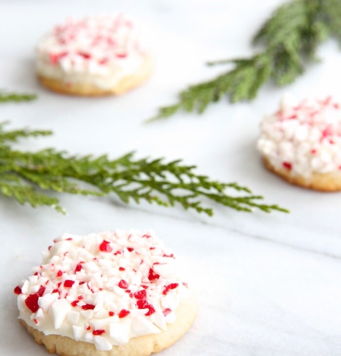 frosted peppermint cookies on marble countertop with holly leaves