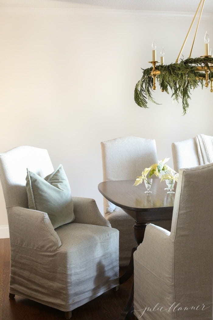 neutral Christmas dining room with simple decorations and a white poinsettia centerpiece on the table