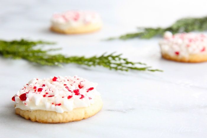 frosted peppermint cookies on marble countertop with holly leaves