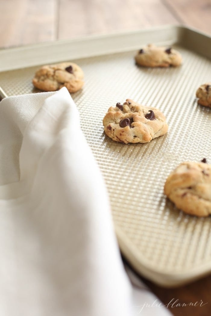 Six chewy chocolate chip cookies on a baking tray