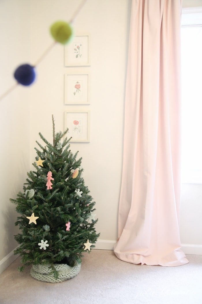 A small christmas tree in a child's bedroom, pink curtains on the window