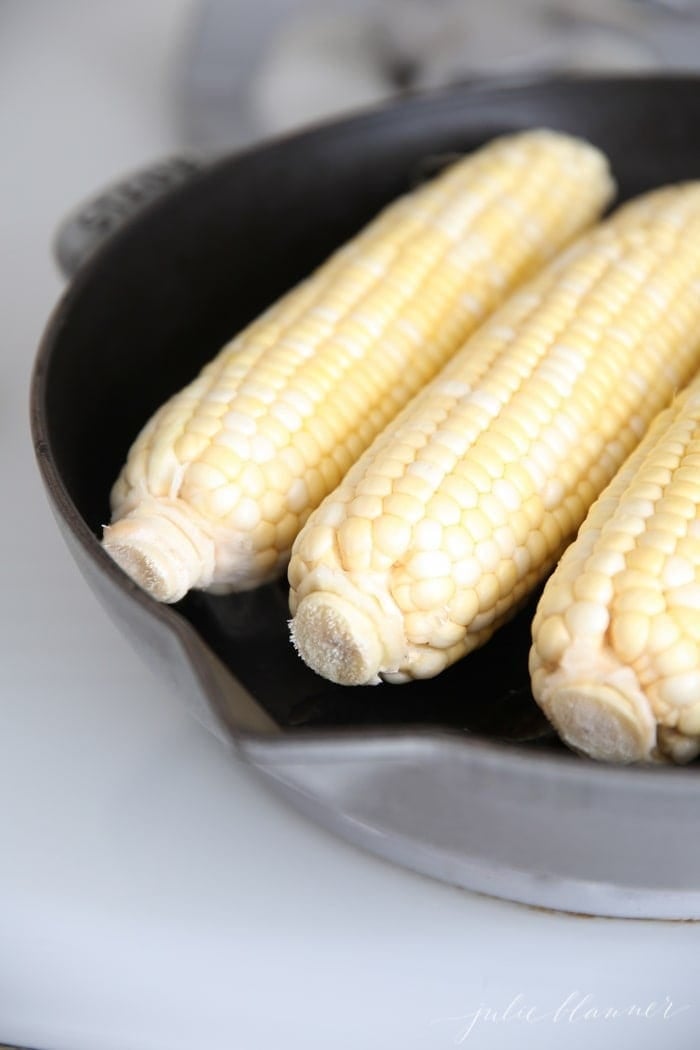 Uncooked corn on the cob in a pan on the stove top