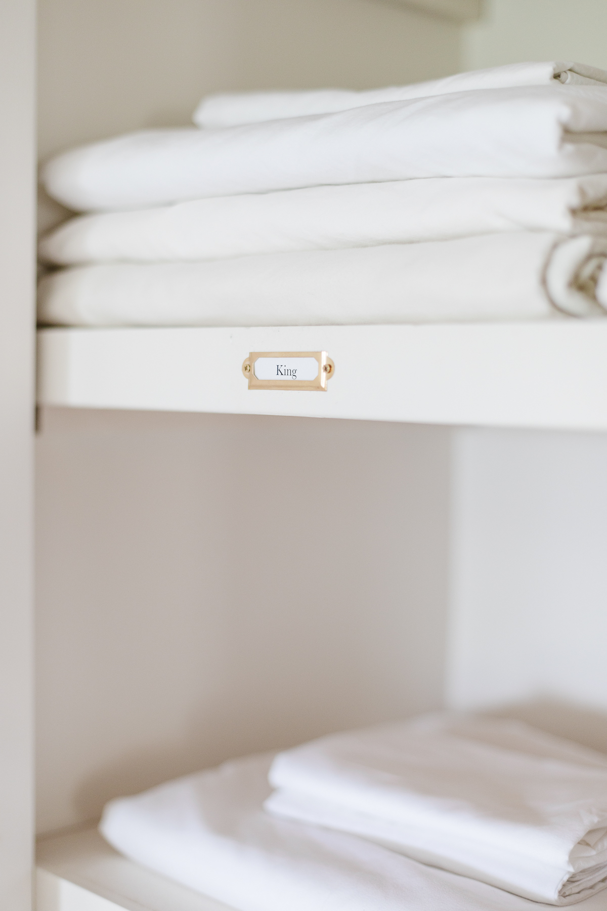 Linens neatly arranged on a shelf in a linen closet.