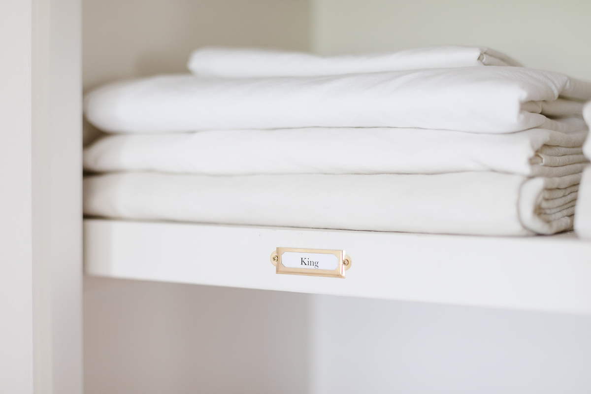 A stack of white towels on a linen closet shelf.