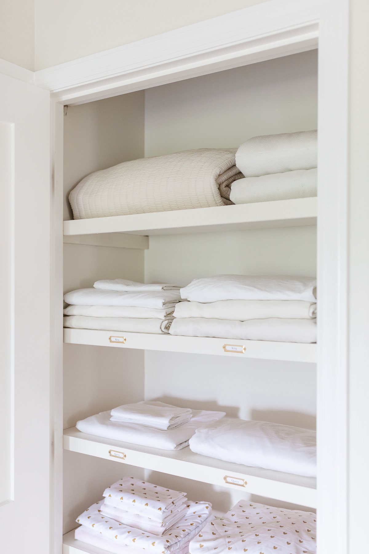A linen closet with white sheets and towels.