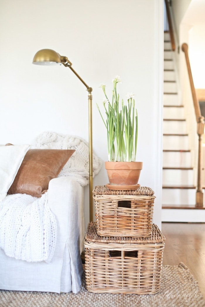 A white living room with storage baskets by the sofa.