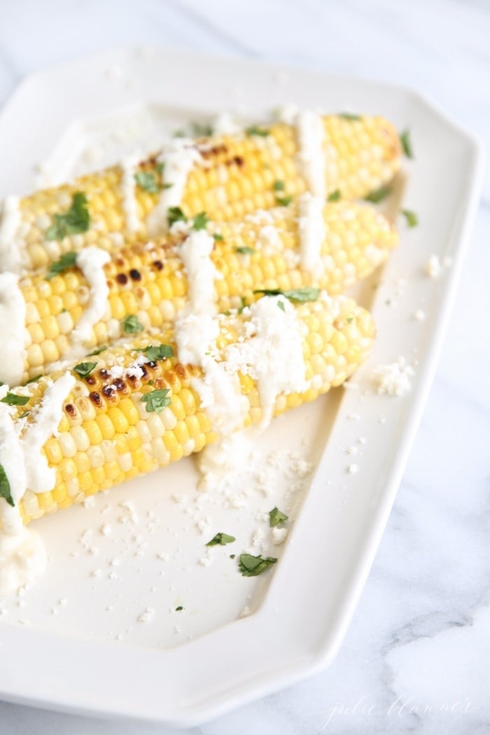 Mexican corn on the cob recipe drizzled with cotija cheese and cilantro on a platter