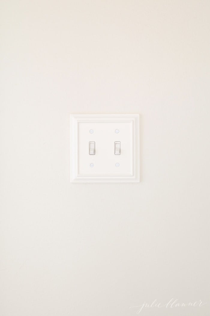 A white wall with a wooden switch plate cover on a light switch.