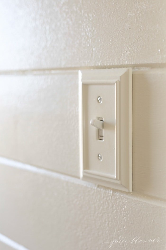 White shiplap walls with a wooden switch plate cover