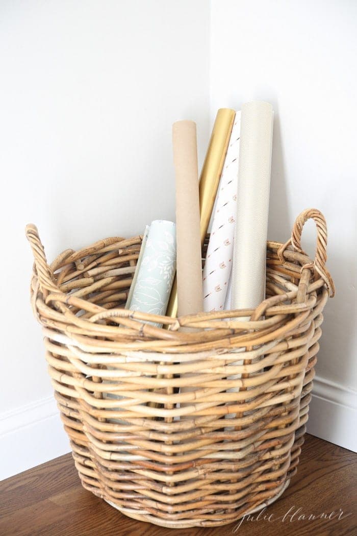 A white room with a basket full of pretty wrapping paper.