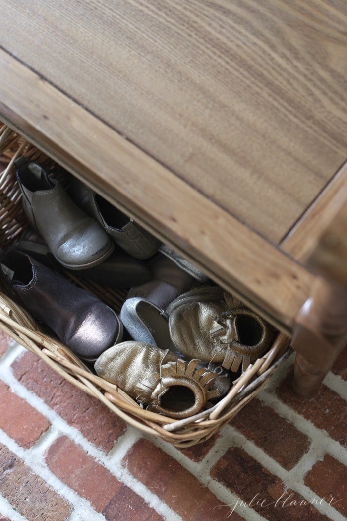 A mudroom bench with a basket full of kid shoes below.