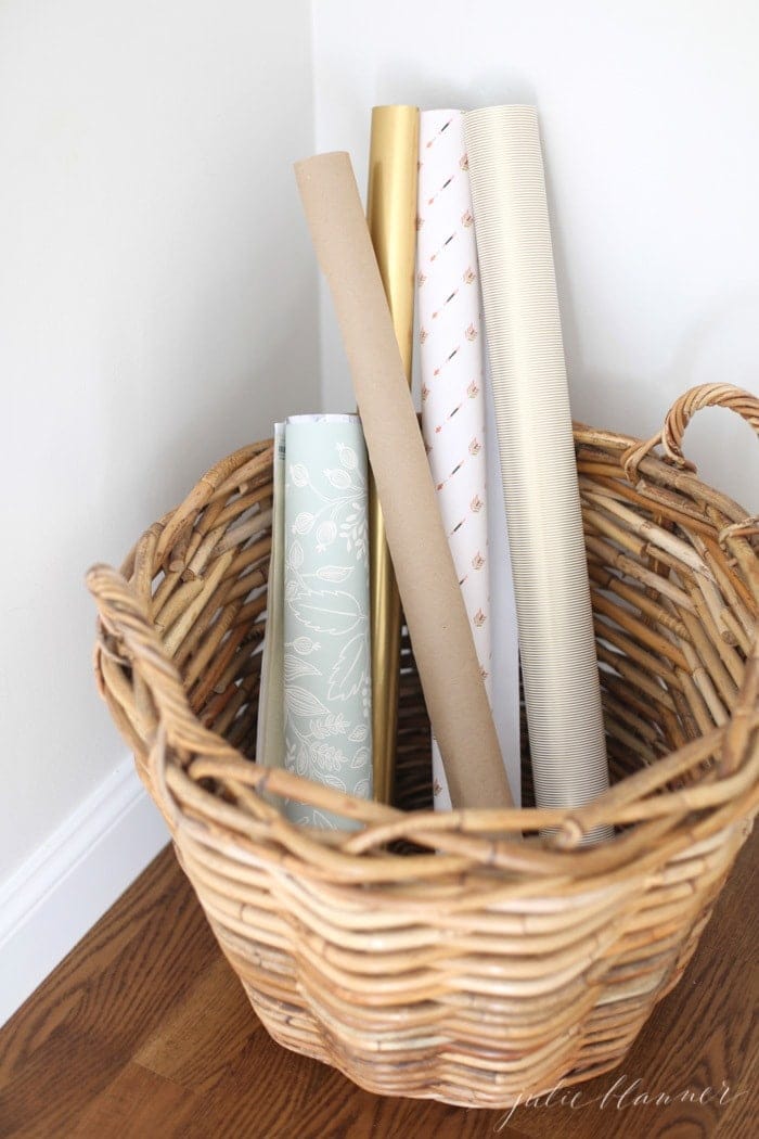 A white room with a basket full of pretty wrapping paper.