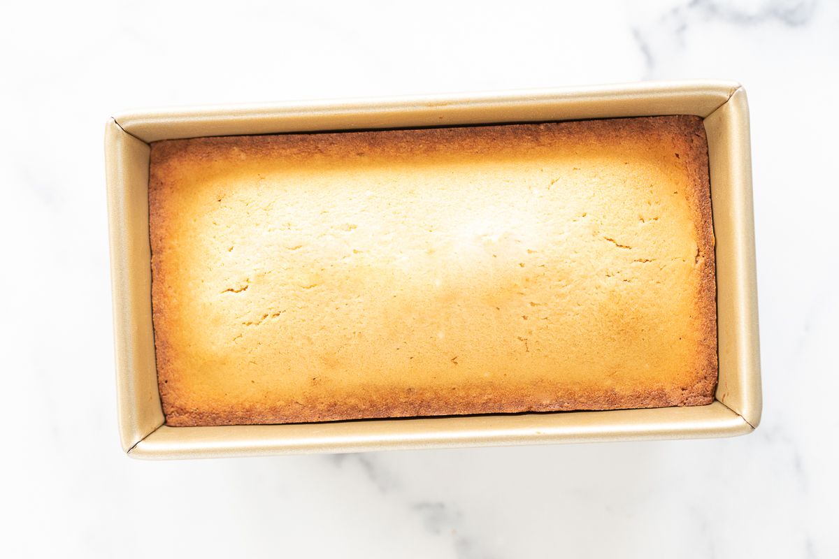 A gold loaf pan filled with an easy pound cake recipe.