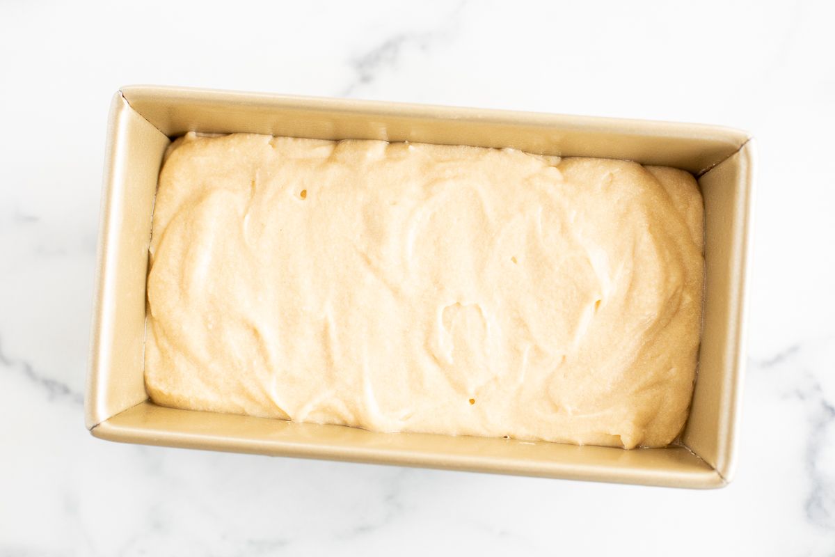 A gold loaf pan filled with batter from an easy pound cake recipe.