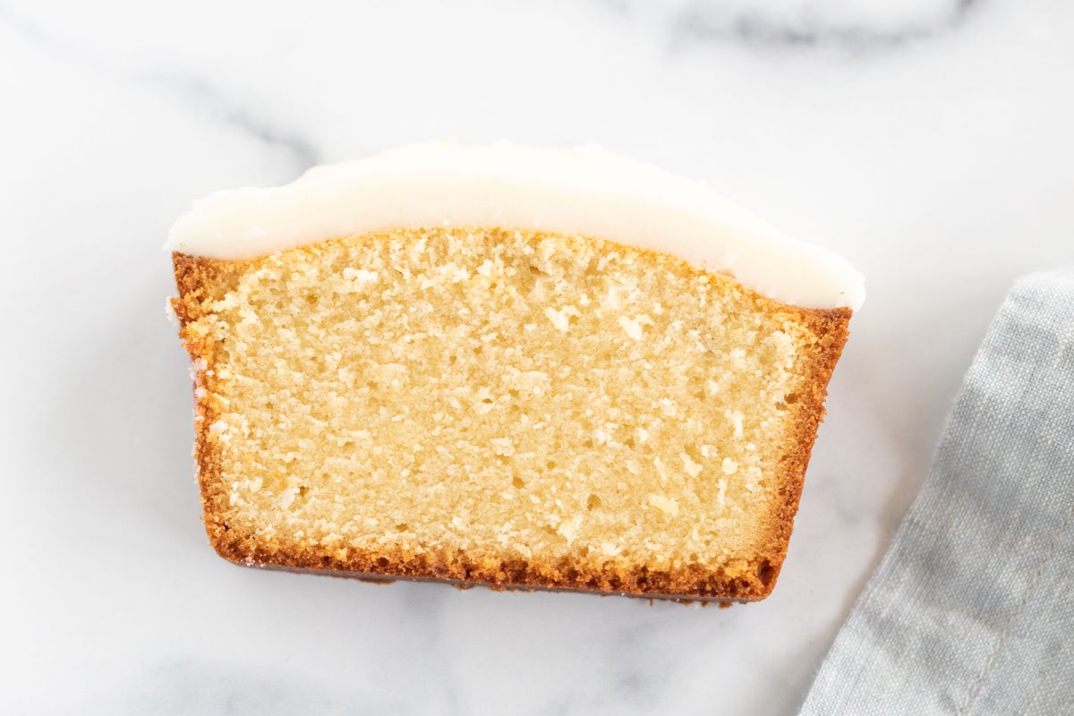A slice of pound cake on a marble countertop, topped with glaze.