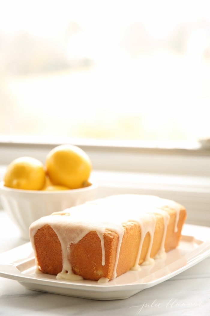 lemon pound cake with a lemon glaze on top, bowl of lemons in the background 