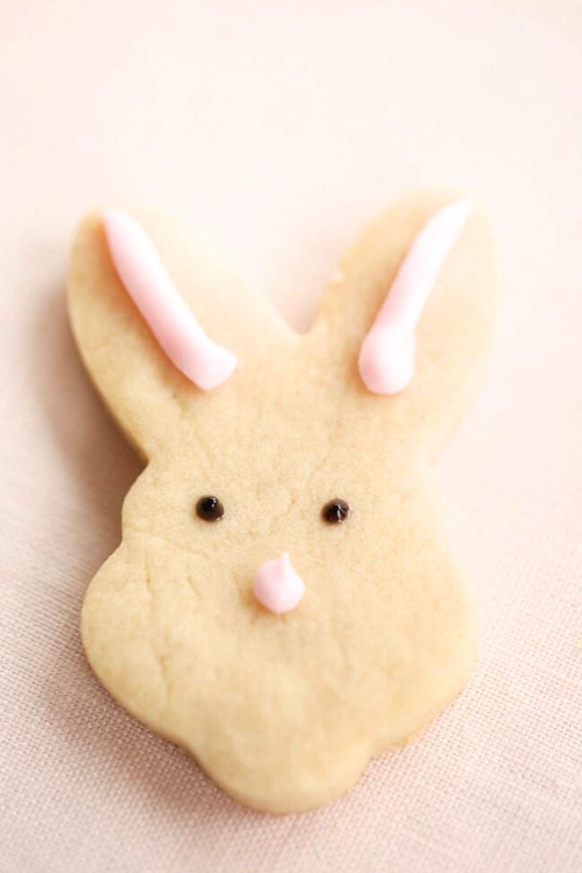 An Easter shortbread cookie in the shape of a bunny face.