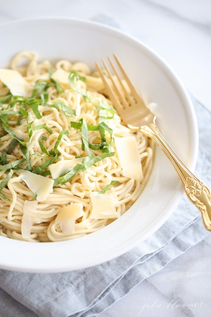 white bowl of lemon basil pasta with a gold fork