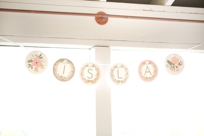 A pale pink floral paper banner with the name Isla
