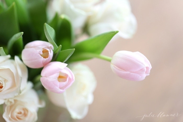 A fresh arrangement of pink tulips and white roses in a clear glass vase.