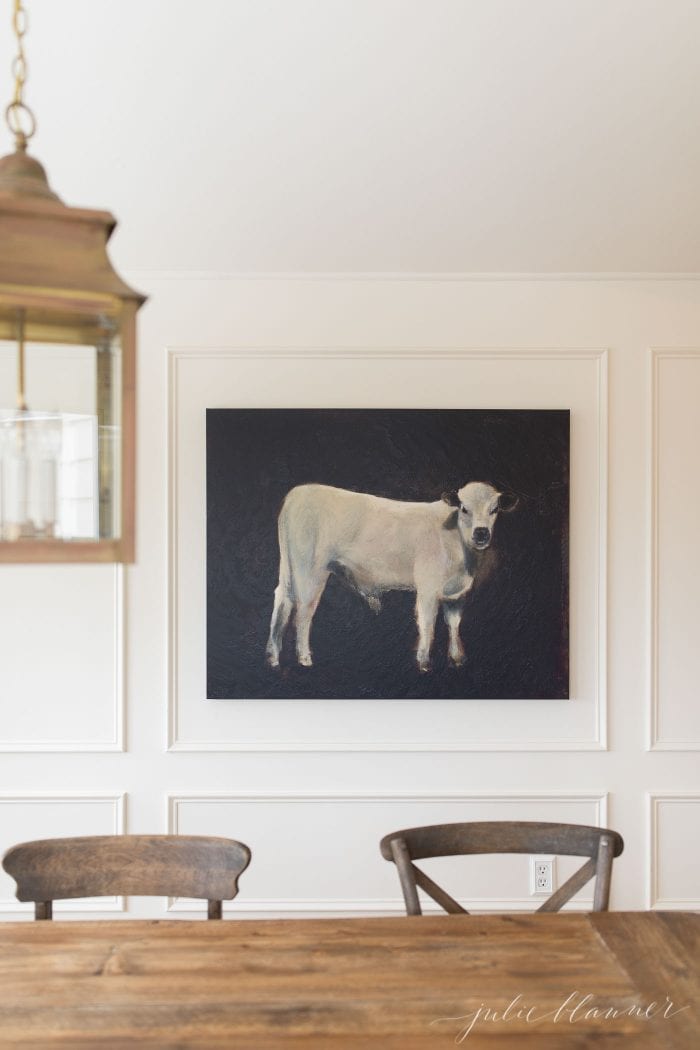 breakfast nook with wood table brass lantern and cow painting