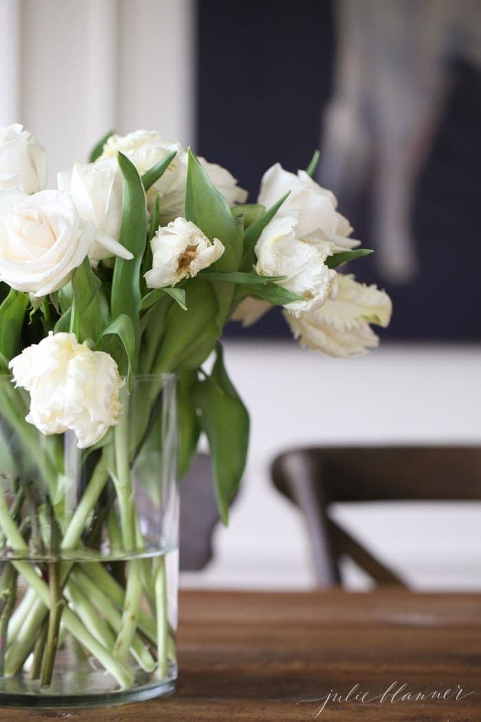 A vase full of white tulips on a breakfast nook table.