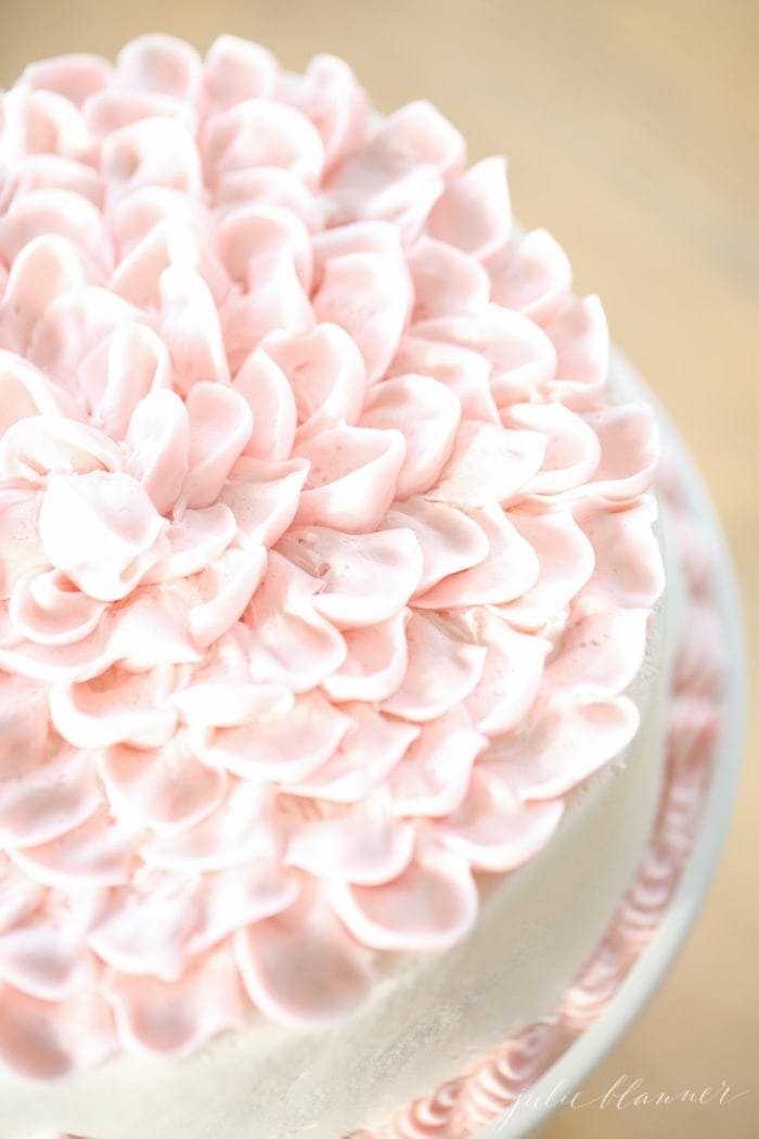 A white cake with pale pink ruffled frosting
