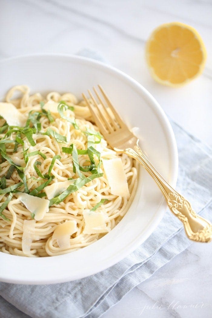 white bowl of lemon basil pasta with gold fork resting on top