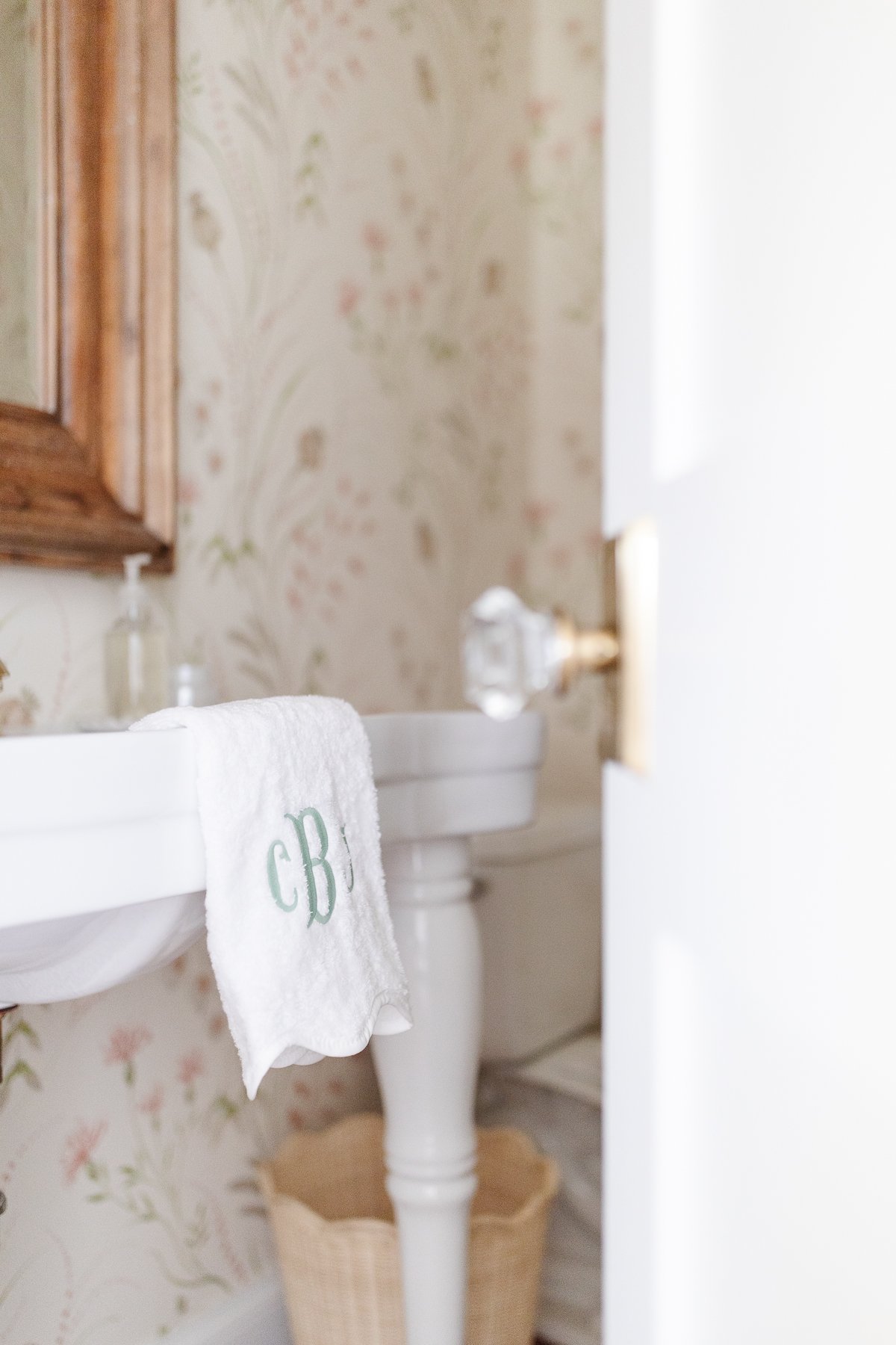 A white pedestal sink with powder room wallpaper in a guest bath