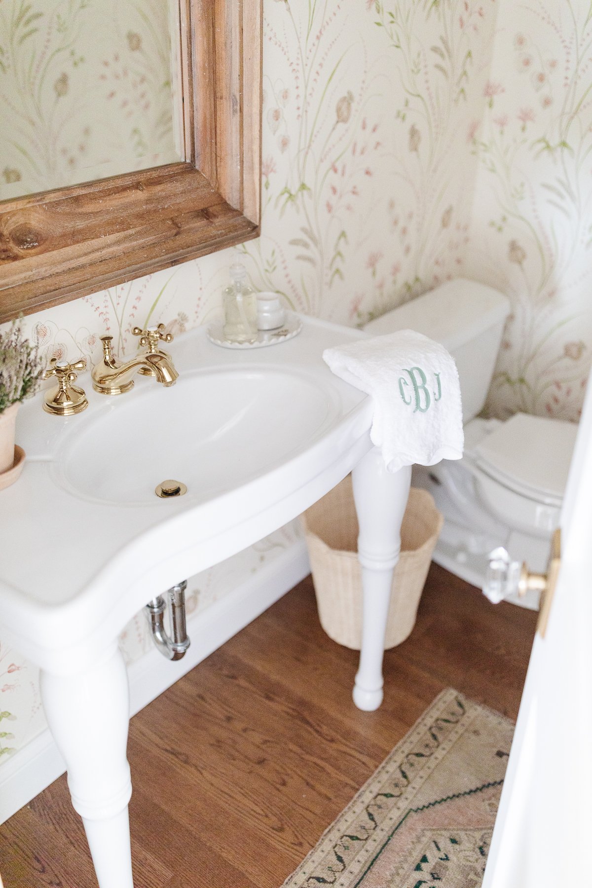 A white pedestal sink with powder room wallpaper in a guest bath