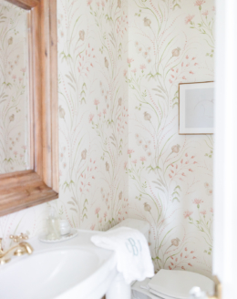 A white pedestal sink with powder room wallpaper in a guest bath