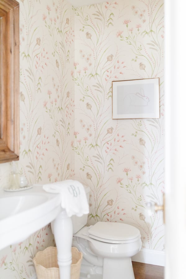 A white pedestal sink with powder room wallpaper in a guest bath
