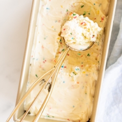 Homemade cake batter ice cream with rainbow sprinkles in a gold loaf pan.
