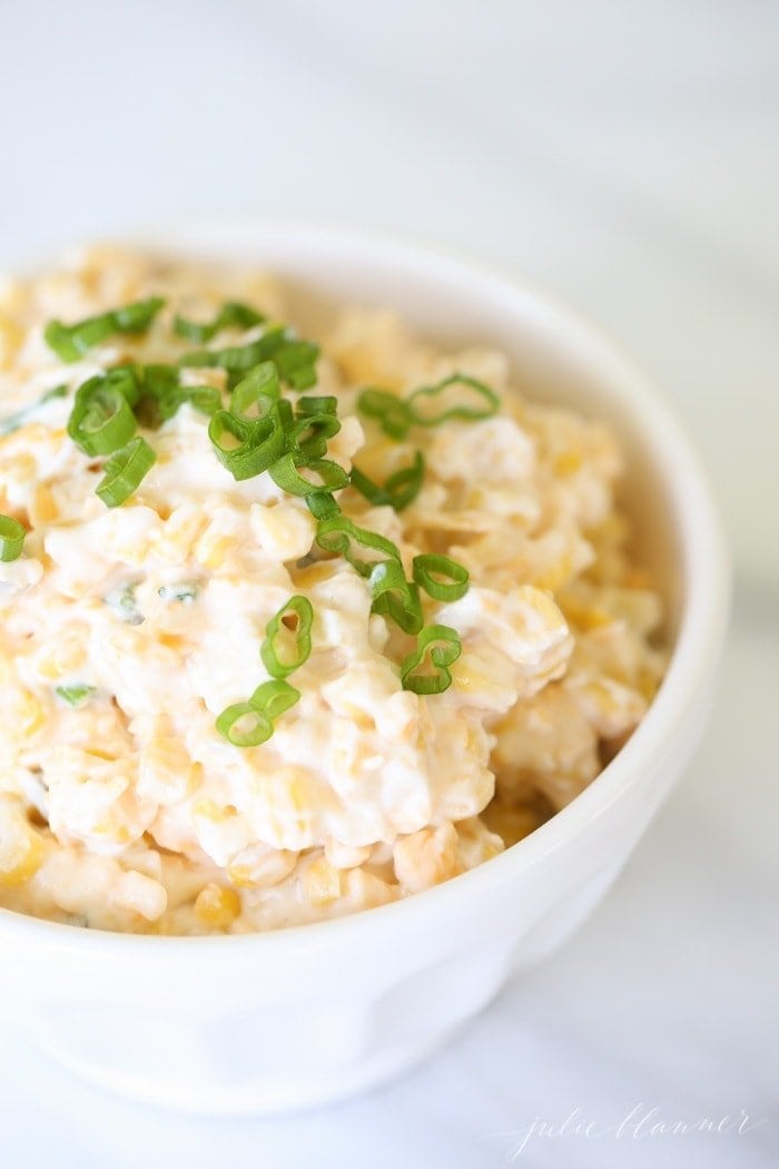 crack corn dip in a white bowl garnished with green onion.