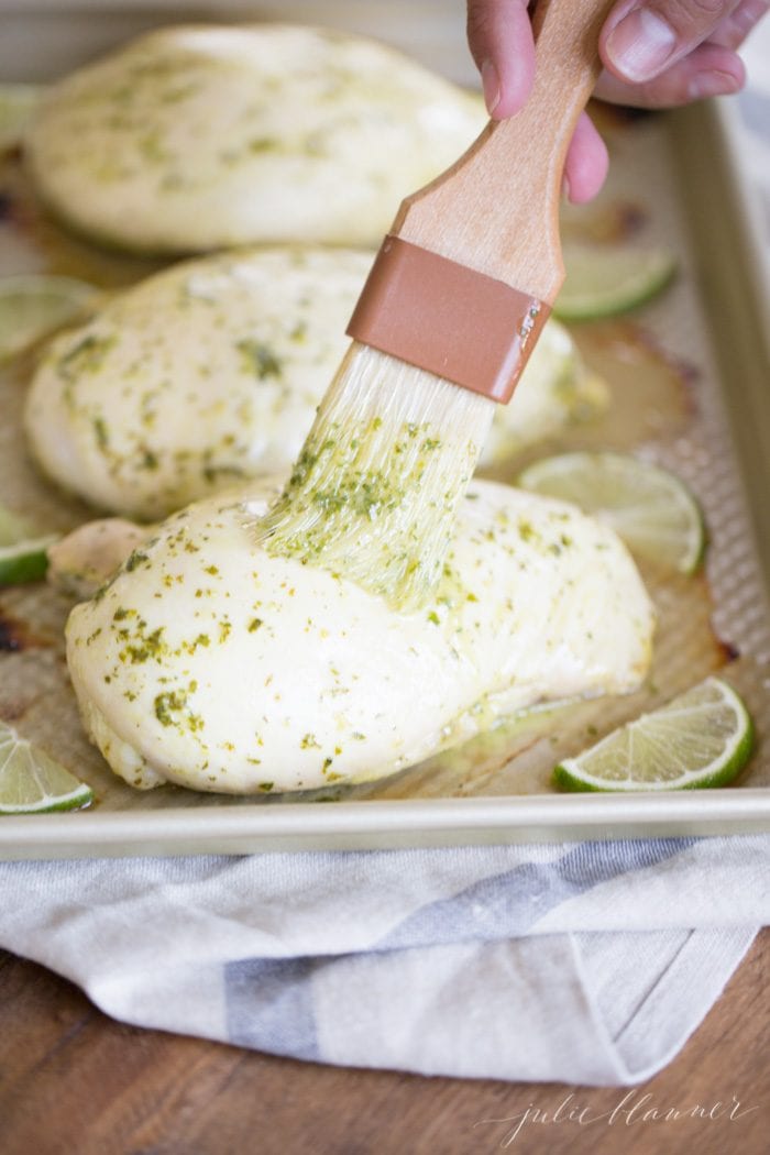 marinade being brushed onto cilantro lime chicken on baking sheet