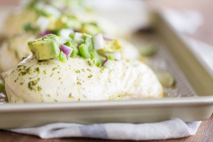 chunky avocado salsa on top of chicken breasts on baking sheet