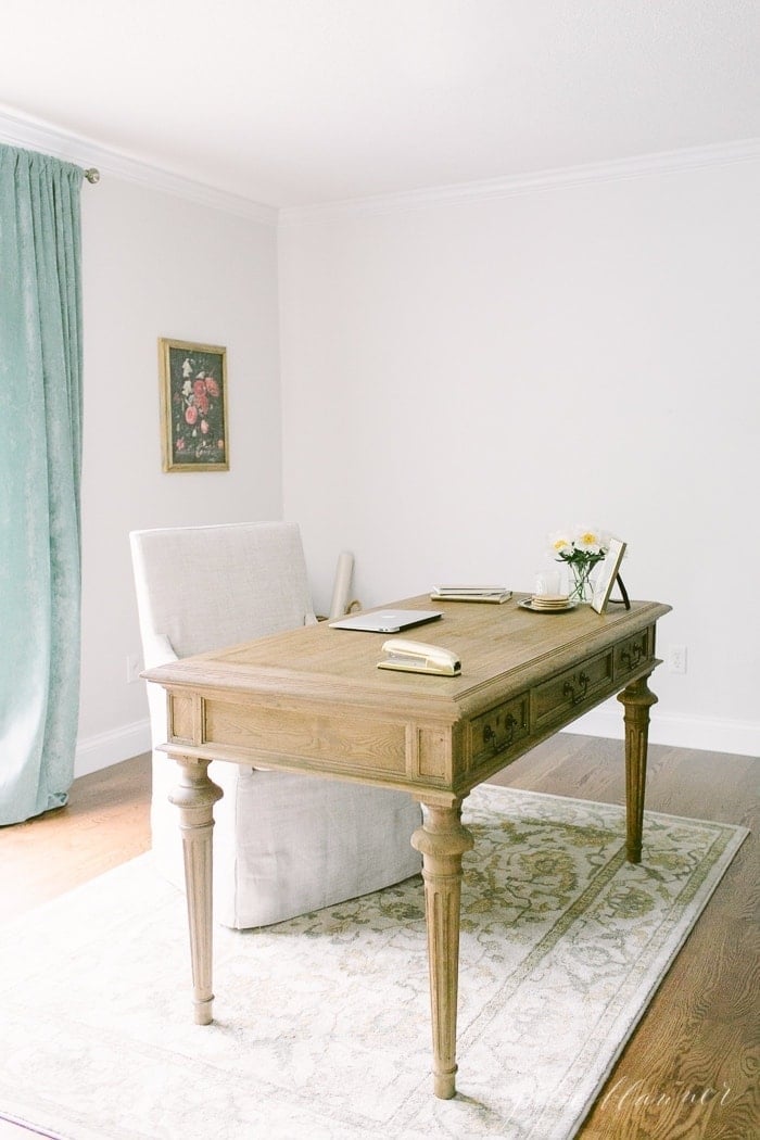 neutral office space with slipcovered chair, velvet curtains and floating desk