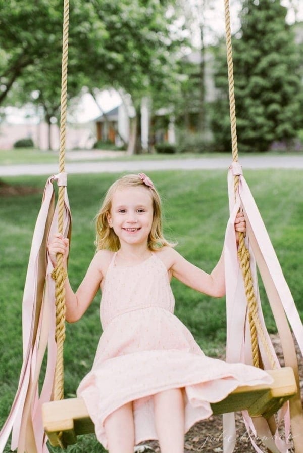 girl on wood tree swing with ribbons tied on it