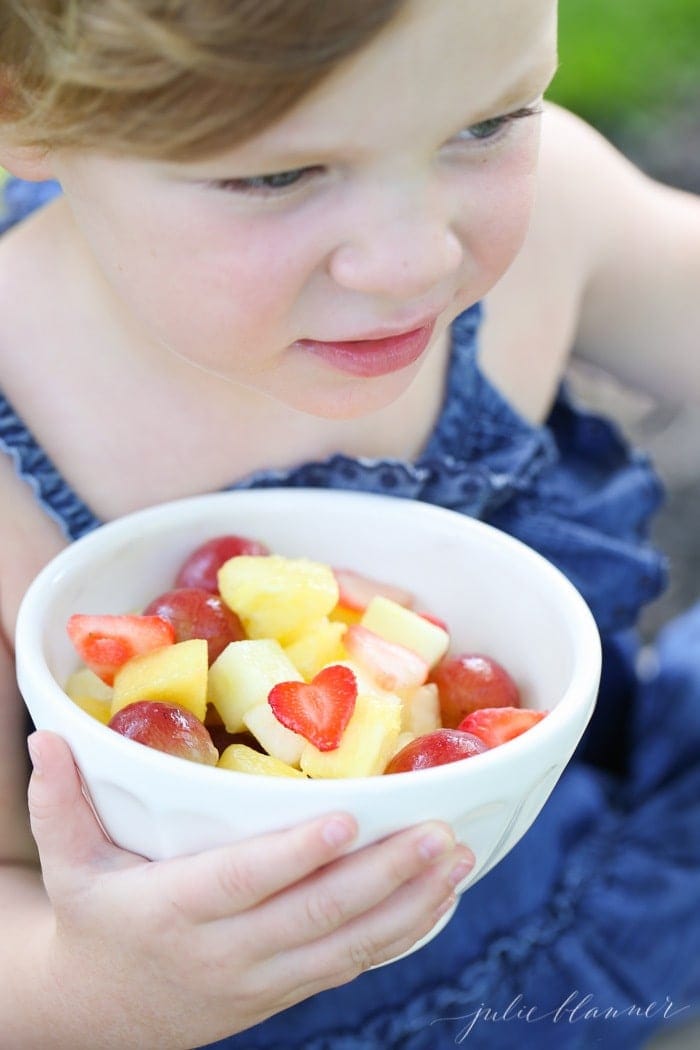 A girl holding a bowl of the fresh snack