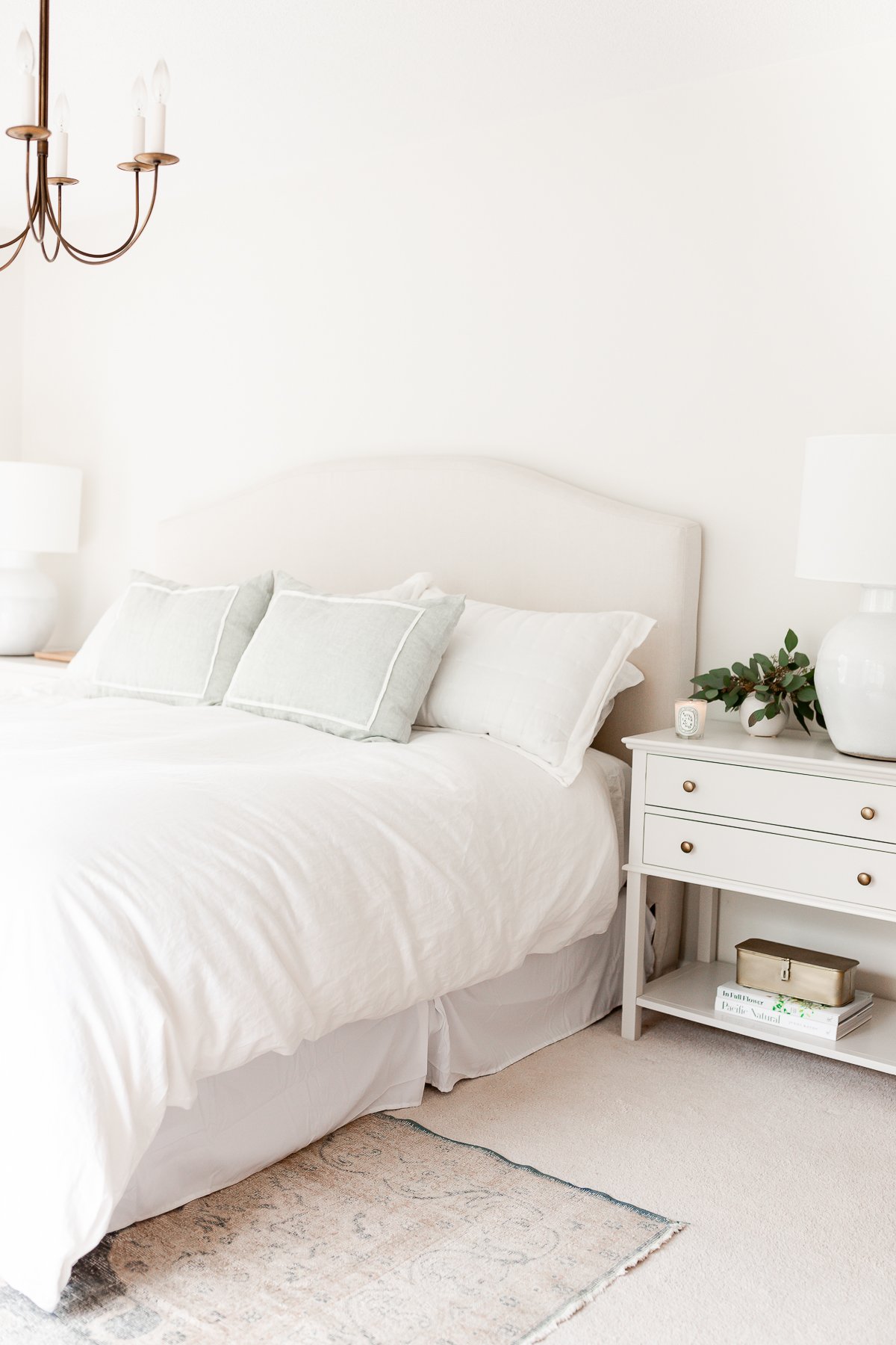 a white bedroom with upholstered headboard