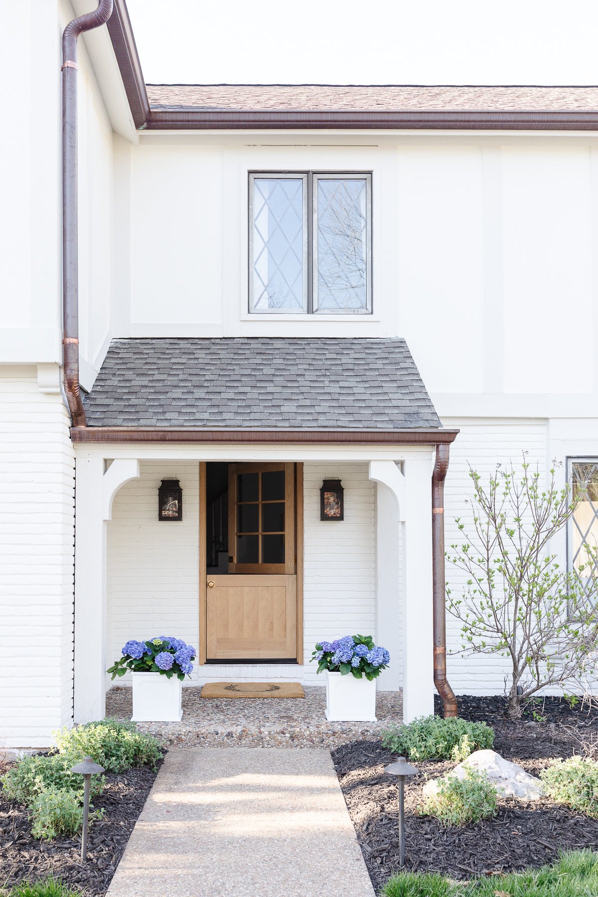 The entry of a white painted home with copper gutters, in a guide to How to Sell a House Fast.