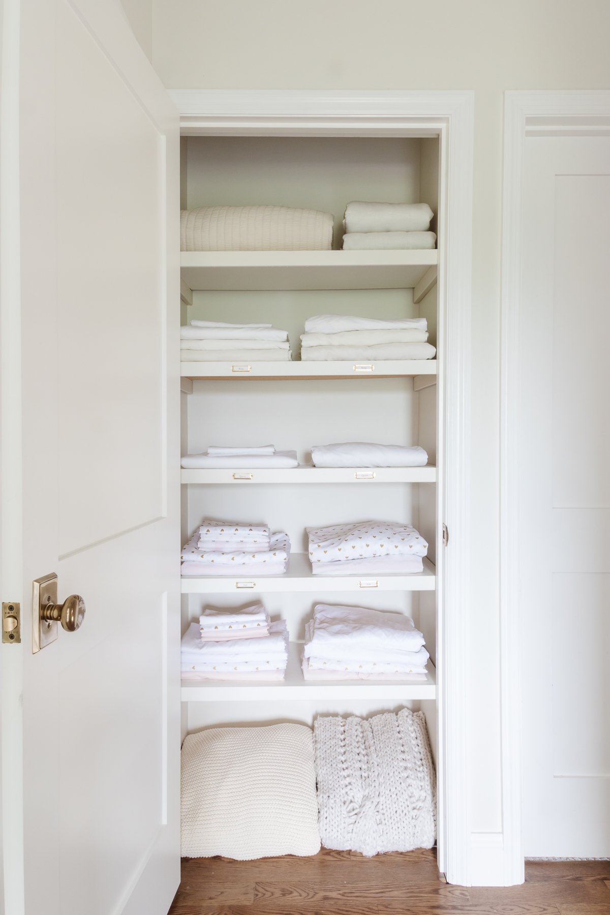 A hallway linen closet with organized white bedding