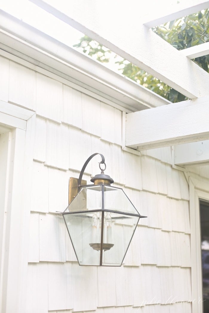 beautiful front porch with a pergola attached to house and a brass lantern