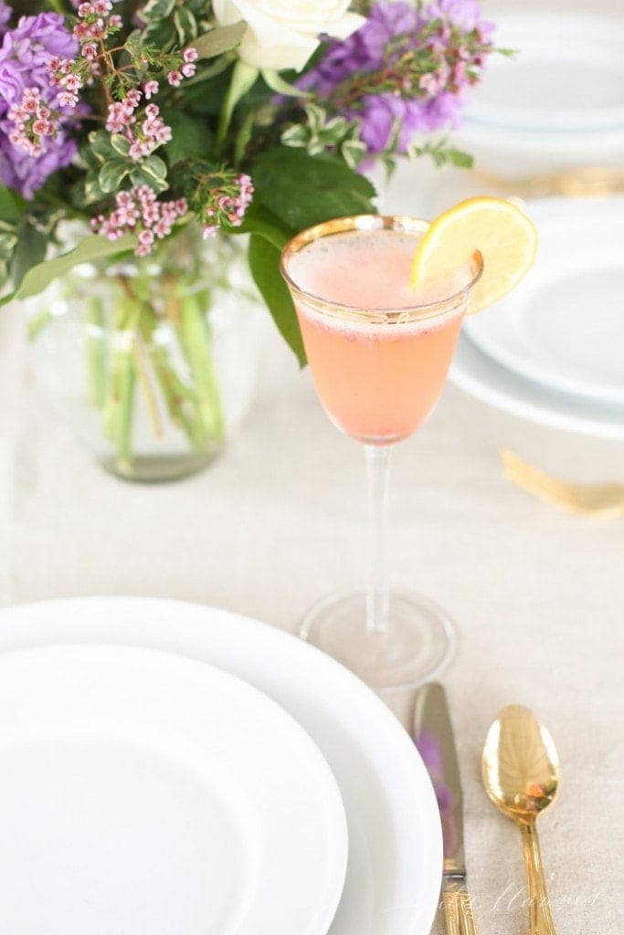A strawberry summer mimosa, garnished with a lemon on a set table. 