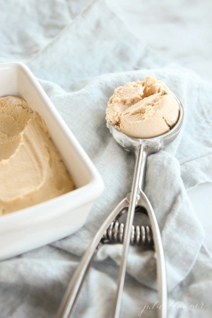 A white loaf pan filled with homemade ice cream, a scoop of ice cream to the side.