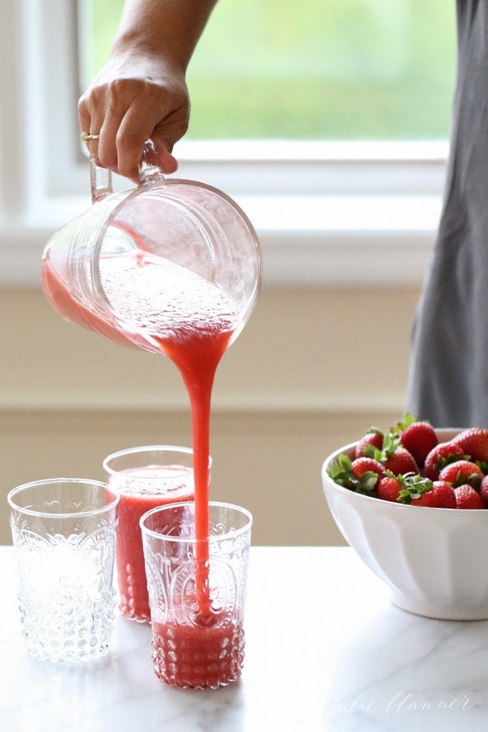 Pouring the strawberry cocktail into tall glasses
